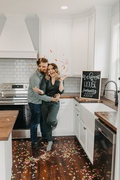 a man and woman standing in a kitchen with confetti falling from the ceiling