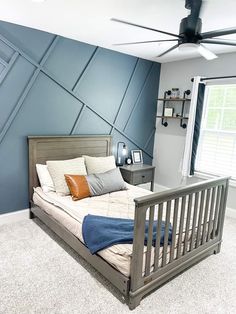 a bed room with a neatly made bed and a ceiling fan in it's corner