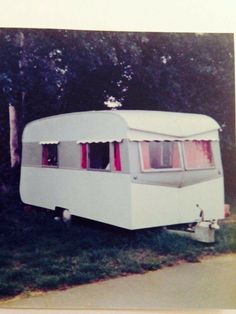 an old photo of a white trailer parked in the grass