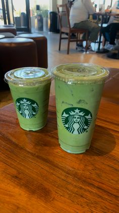 two starbucks drinks sitting on top of a wooden table