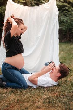 a pregnant woman sitting on the ground next to a man