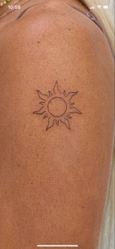 the back of a woman's shoulder with a sun tattoo on it