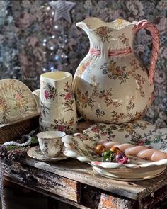 a table topped with plates and cups next to a vase