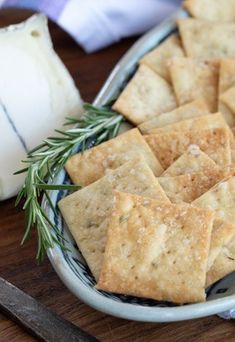 crackers with rosemary sprigs on a plate next to a knife and butter