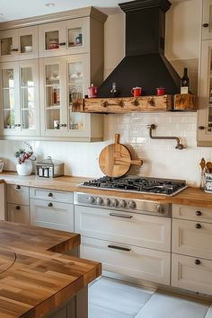 a kitchen with white cabinets and wooden counter tops, an oven hood over the stove