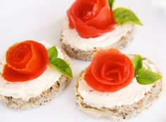 three small sandwiches with cream cheese and red rose on top, sitting next to each other