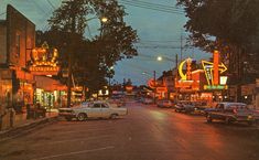 cars are parked on the street in front of some buildings at night with neon signs