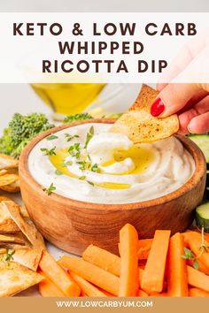 a wooden bowl filled with white dip surrounded by vegetables and crackers