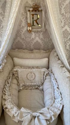 a baby crib in the corner of a room with white curtains and pillows on it