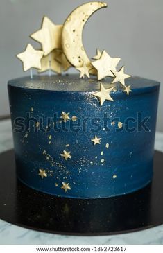 a blue cake with gold stars on top and the moon in the sky above it