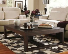 a living room with two couches, a coffee table and vases on the floor