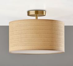 a light fixture with a beige fabric shade on the bottom and gold trim around it