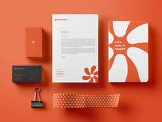 an orange and white stationery set on top of a red surface with a key