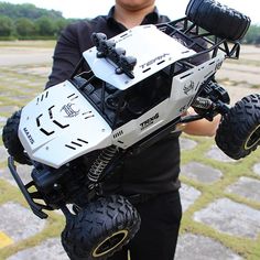 a person holding a remote control vehicle in their right hand and the camera attached to it