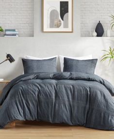 a bedroom with white brick walls and grey bedding