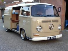 an old vw bus is parked in front of a brick building with its door open