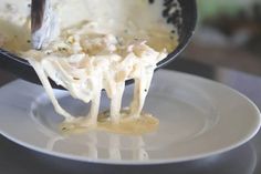 a person is scooping cheese from a skillet into a white bowl on a plate