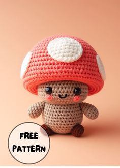 a small crocheted mushroom with a white dot on it's face sitting in front of a pink background