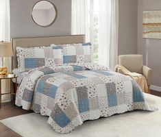 a bed in a bedroom with a blue and white quilt