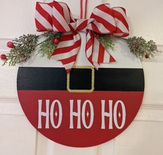 a christmas ornament hanging on a door with red and white striped ribbon around it