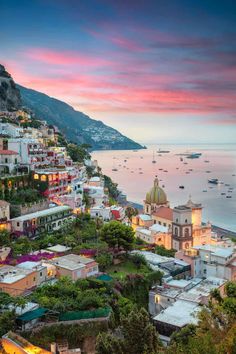 an aerial view of the town of positi at sunset with boats in the water