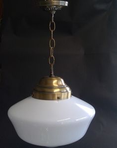 a white and gold light hanging from a ceiling fixture in a dark room with black walls