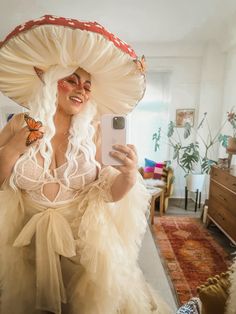 a woman in a white dress is taking a selfie with her phone and butterfly wings