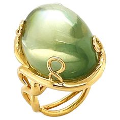 Synonymous with its name, a significant size of moonlit gemstone in everyday design serves as a timeless jeweled piece. Adularescence glows within this ring, an effect that resembles the appearance of a shimmering moon. The featured jewel is a mango moonstone with beautiful shades of green, mainly neutral sage, fashioned into an oval cabochon. When light strikes the surface of a gemstone, it exhibits a floating sheen like the moon. Depending on the angle, it also displays an attractive light and shades. The moonstone is set between four pieces of twisted 18k yellow gold woven into prongs. Underneath is a double shank that stretches like vines. The weight is 34.9 carats of moonstone. The ring measures 0.85 inches (width) by 1.06 inches (length) by 1.34 inches (height) by 0.59 inches (depth) Moonstone Ring, Oval Cabochon, Shades Of Green, Fashion Rings, Moonstone, The Moon, Vines, Vintage Jewelry, Jewelry Rings