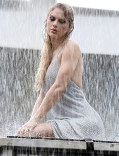 a woman sitting on top of a wooden bench in the rain