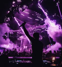 a man standing in front of a crowd at a concert with his arms raised up