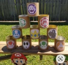 some paper cups that have mario and luigi's faces on them in front of a fence