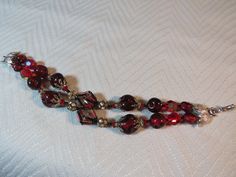 Very pretty silver tone Vendome signed two strand bead bracelet includes black glass seed beads, deep red glass beads with a lumpy surface and faceted red aurora borealis glass beads.  There are also red glass tube beads surrounding the 2 main center glass beads and rhinestone rhondells.   There are pretty silver and rhinestone bead caps.  The bracelet is about 8" long.  The bracelet is in good condition with a secure clasp.  The metal is clean and the beads are in good condition. Red Aurora Borealis, Glass Bead Bracelet, Glass Beaded Bracelets, Rhinestone Bead, Glass Seed Beads, Tube Beads, Bead Caps, Red Glass, Aurora Borealis