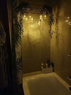 a bath tub sitting under a bathroom mirror next to a shower curtain with lights on it