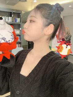 a woman holding up a stuffed animal in front of a book shelf filled with books