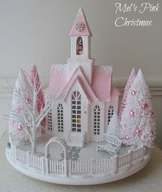 a pink and white christmas house with trees