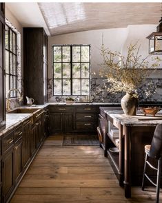 a kitchen with wooden floors and dark wood cabinetry, along with a large window