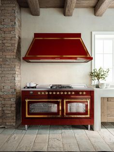 a red stove top oven sitting inside of a kitchen next to a counter and window