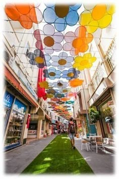 an indoor shopping mall with artificial grass and colorful lights hanging from it's ceiling