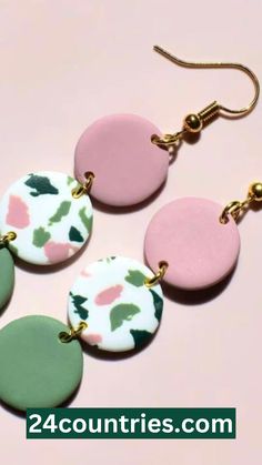 four different colored earrings on a pink and green background