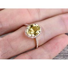 a woman's hand holding an oval yellow diamond ring