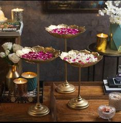 three trays with flowers on them sitting on a table next to candles and other items