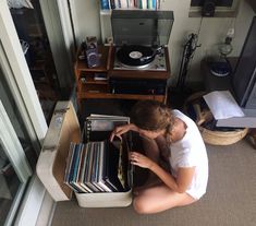 a woman sitting on the floor next to a record player