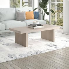 a living room with a white couch and wooden coffee table in front of large windows