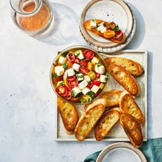 an assortment of breads and vegetables on a tray next to a glass of beer