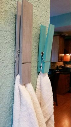 two towels are hanging on the wall next to a pair of wooden clothes pegs