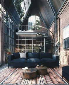 a living room filled with lots of furniture next to a spiral stair case in an old building