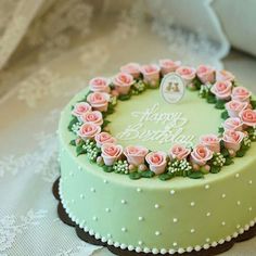 a birthday cake decorated with pink roses on a table