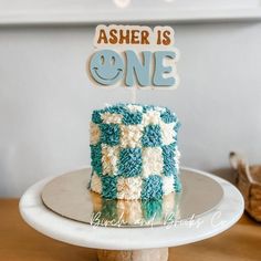 a blue and white cake sitting on top of a table next to a wooden sign