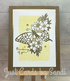 an easel holding a card with a butterfly and flowers on it, which reads just cards by sandi