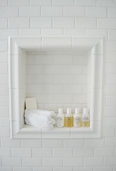 a white shelf with bottles and towels on it